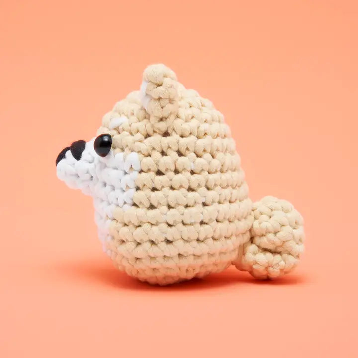 Side view of a beige and white crocheted shiba inu